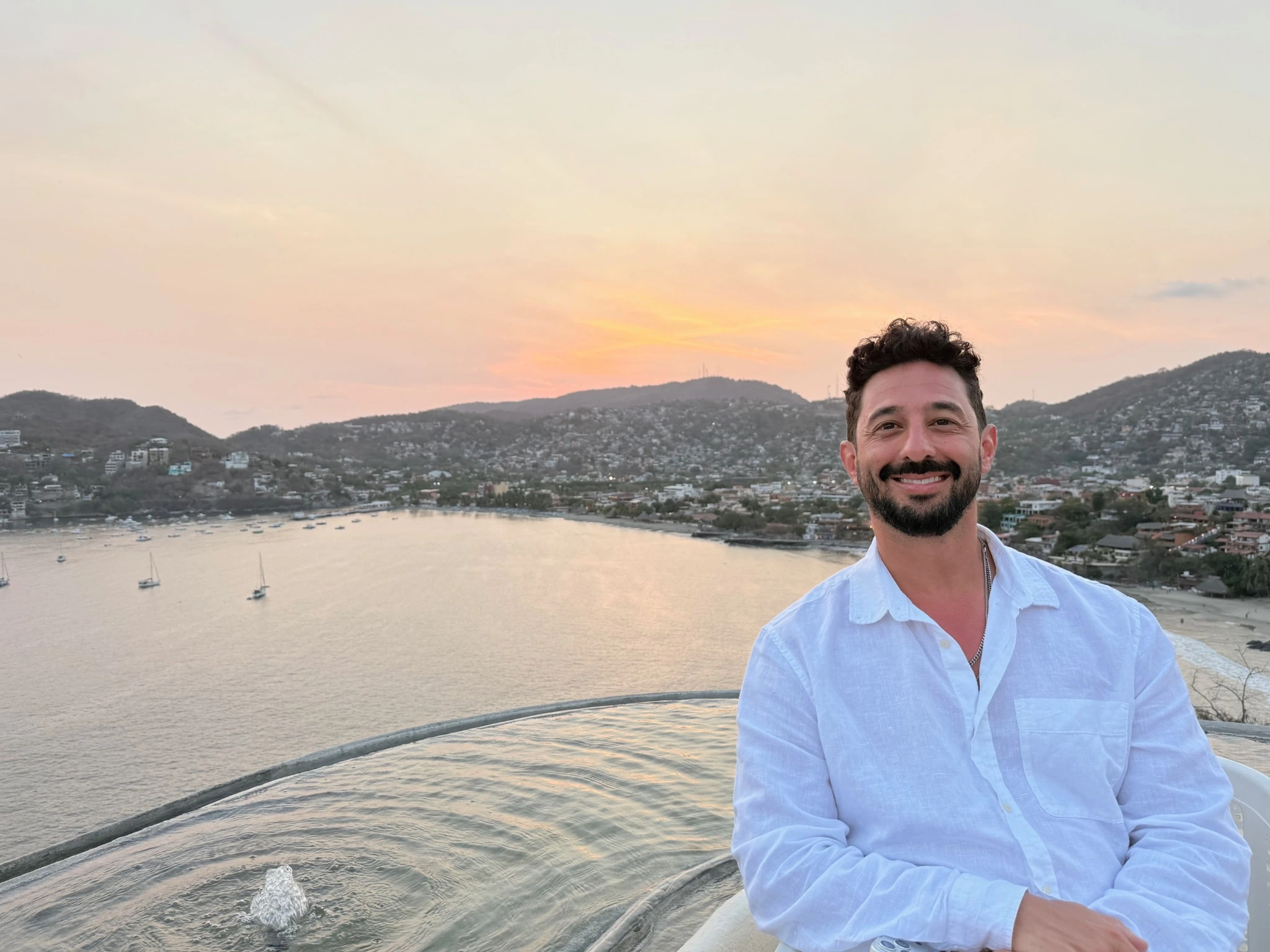 Amad Ebrahimi, founder of Route House, overlooking a coastal bay at sunset.